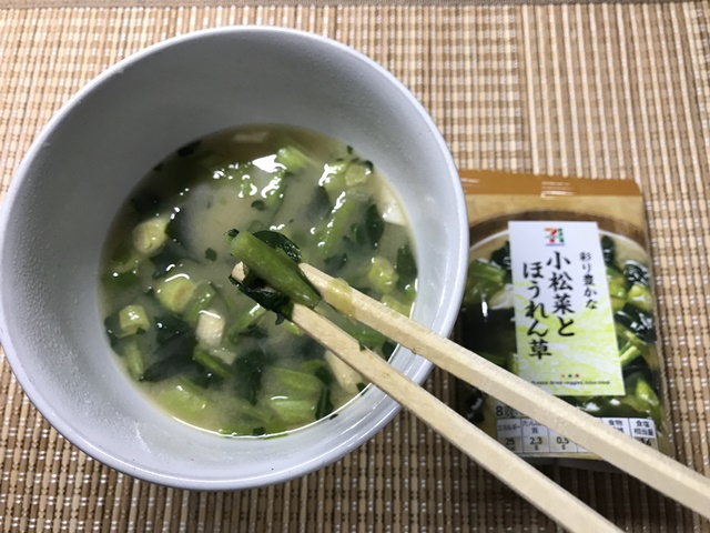セブンプレミアム：彩り豊かな小松菜とほうれん草　味噌汁の具を箸でつまんだところ